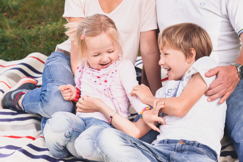 Geschwister toben fröhlich auf einer Picknickdecke