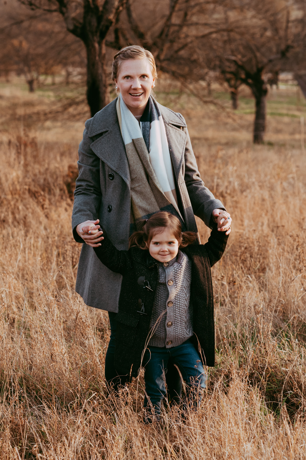 Mama und Tochter laufen Hand in Hand im hohen Gras