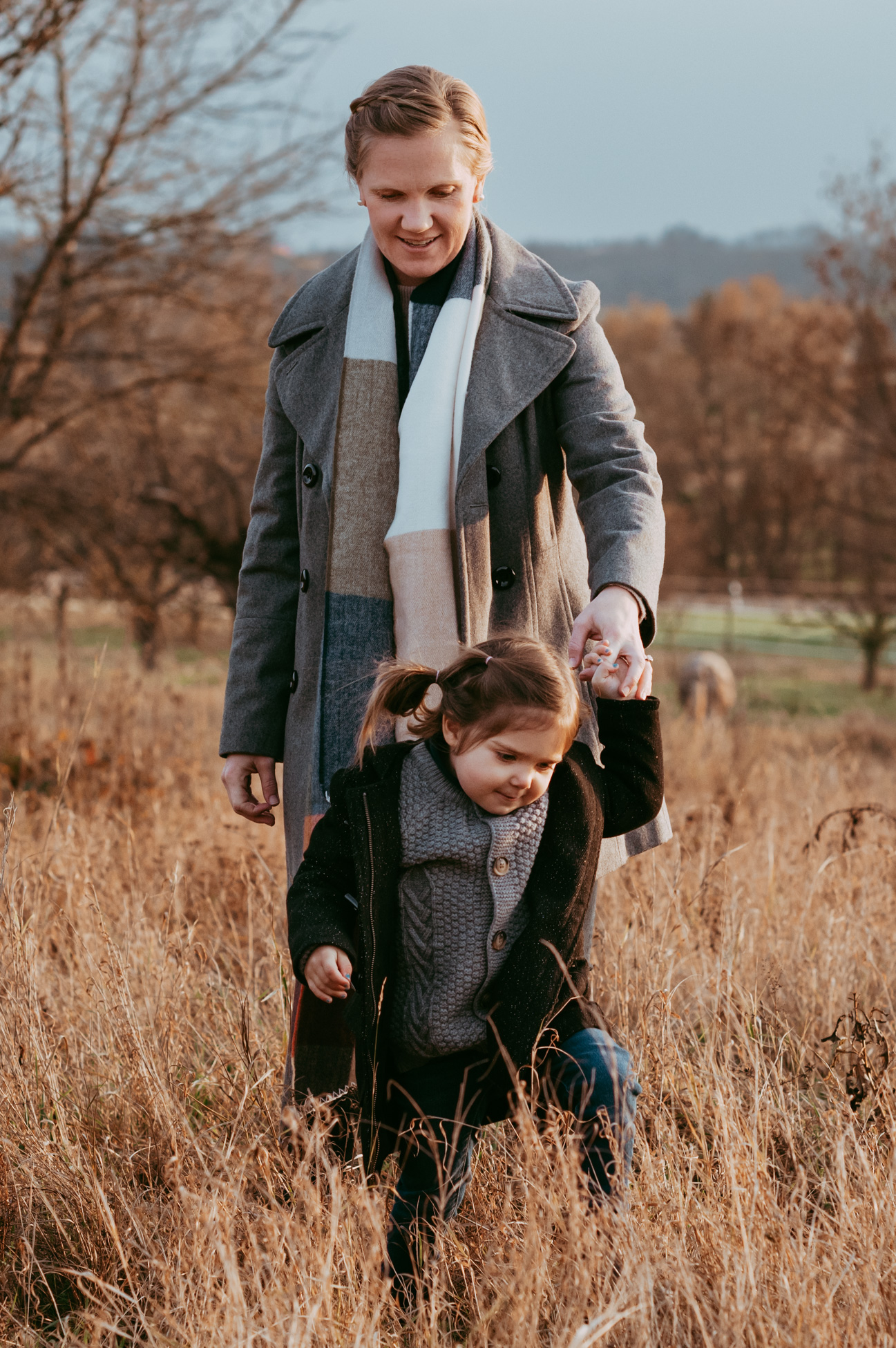 Mama und Tochter laufen Hand in Hand im hohen Gras