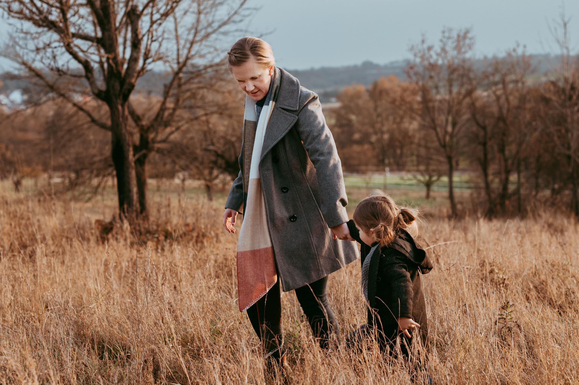 Mama und Tochter laufen Hand in Hand im hohen Gras