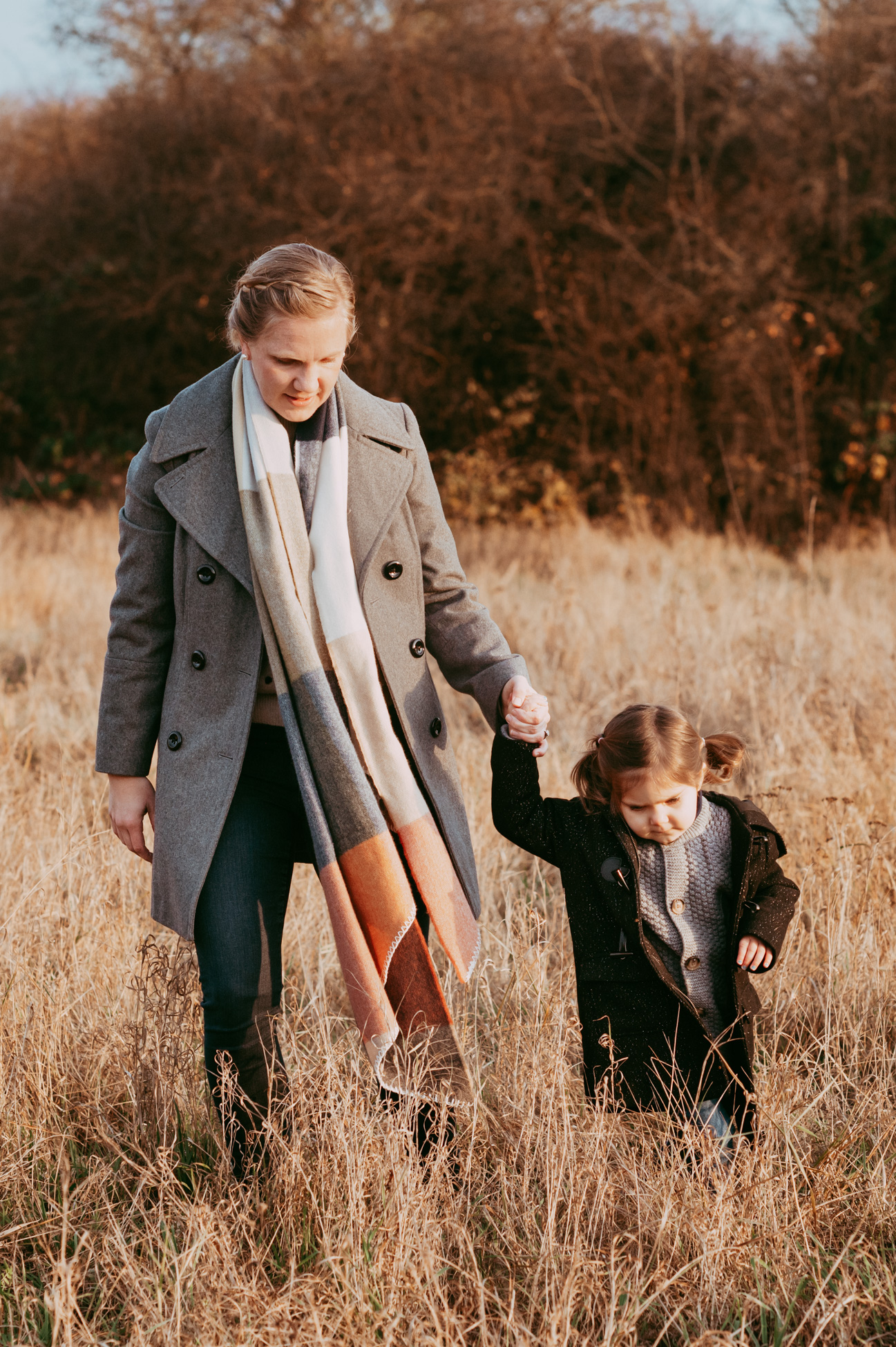 Mama und Tochter laufen Hand in Hand im hohen Gras